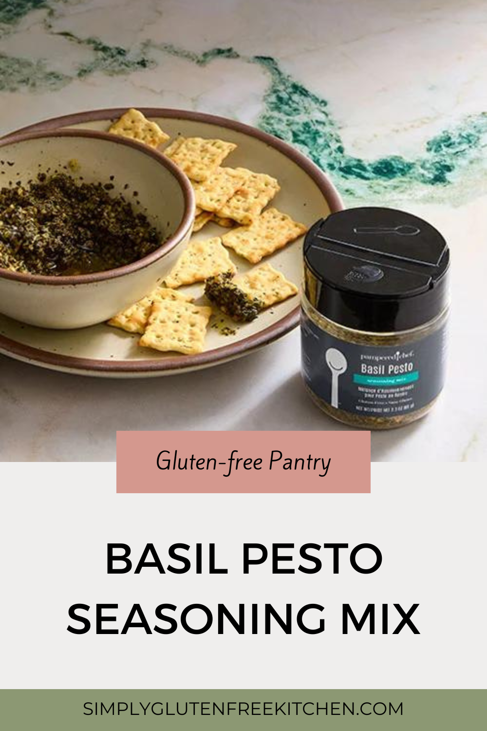 A bowl of basil pesto seasoning mix on a plate with several gluten-free crackers. A jar of Pampered Chef Basil Pesto Seasoning Mix is placed next to the plate, showcasing the product in an inviting and appetizing setting