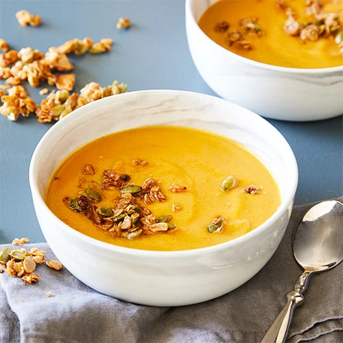 A warm bowl of creamy gluten-free butternut squash soup topped with seeds for a fall-inspired dish.