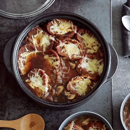 A hearty bowl of gluten-free French onion and mushroom soup topped with cheesy bread.