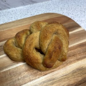 Freshly baked gluten-free soft pretzels with a golden crust, arranged on a wooden board.