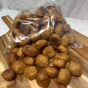 A bag of golden-brown gluten-free soft pretzel bites spilling onto a wooden board.