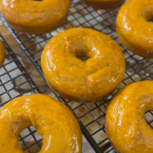 Gluten-free pumpkin donuts topped with shiny brown sugar glaze.